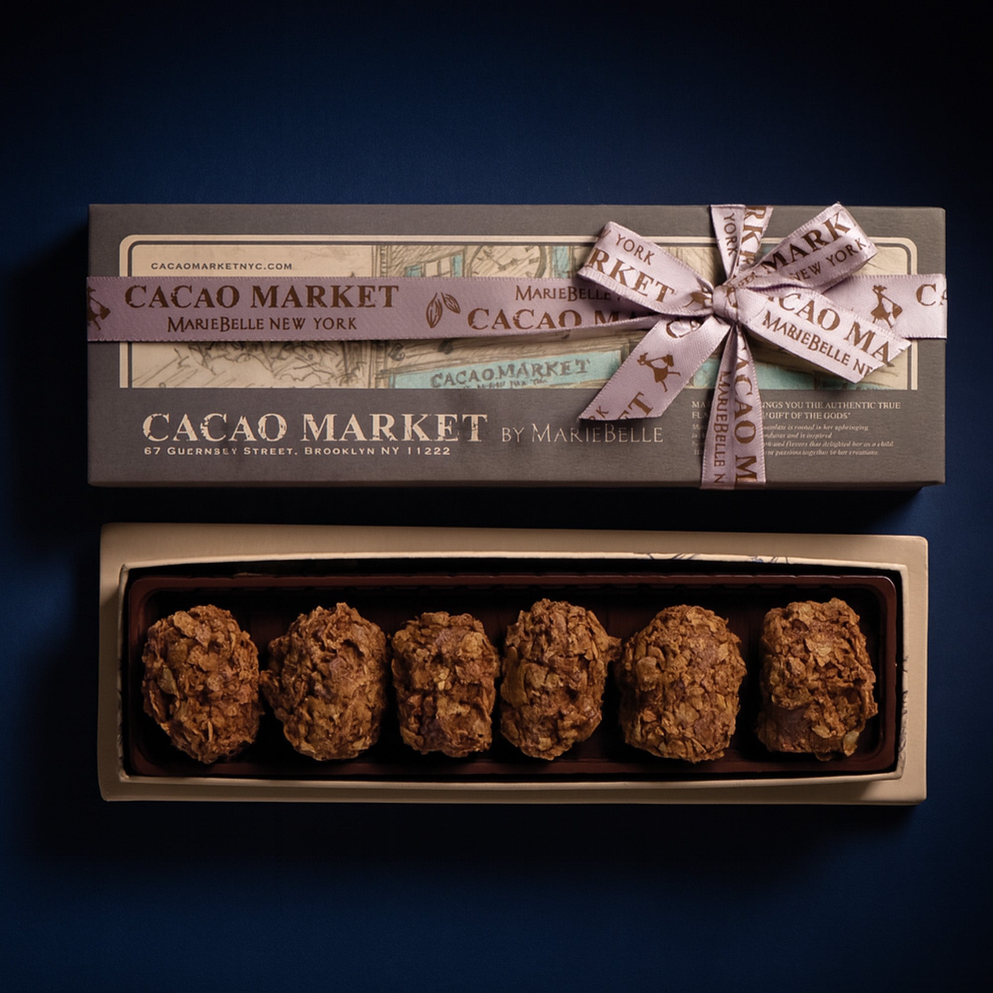 Box of Cacao Market truffles with a decorative bow on a dark background