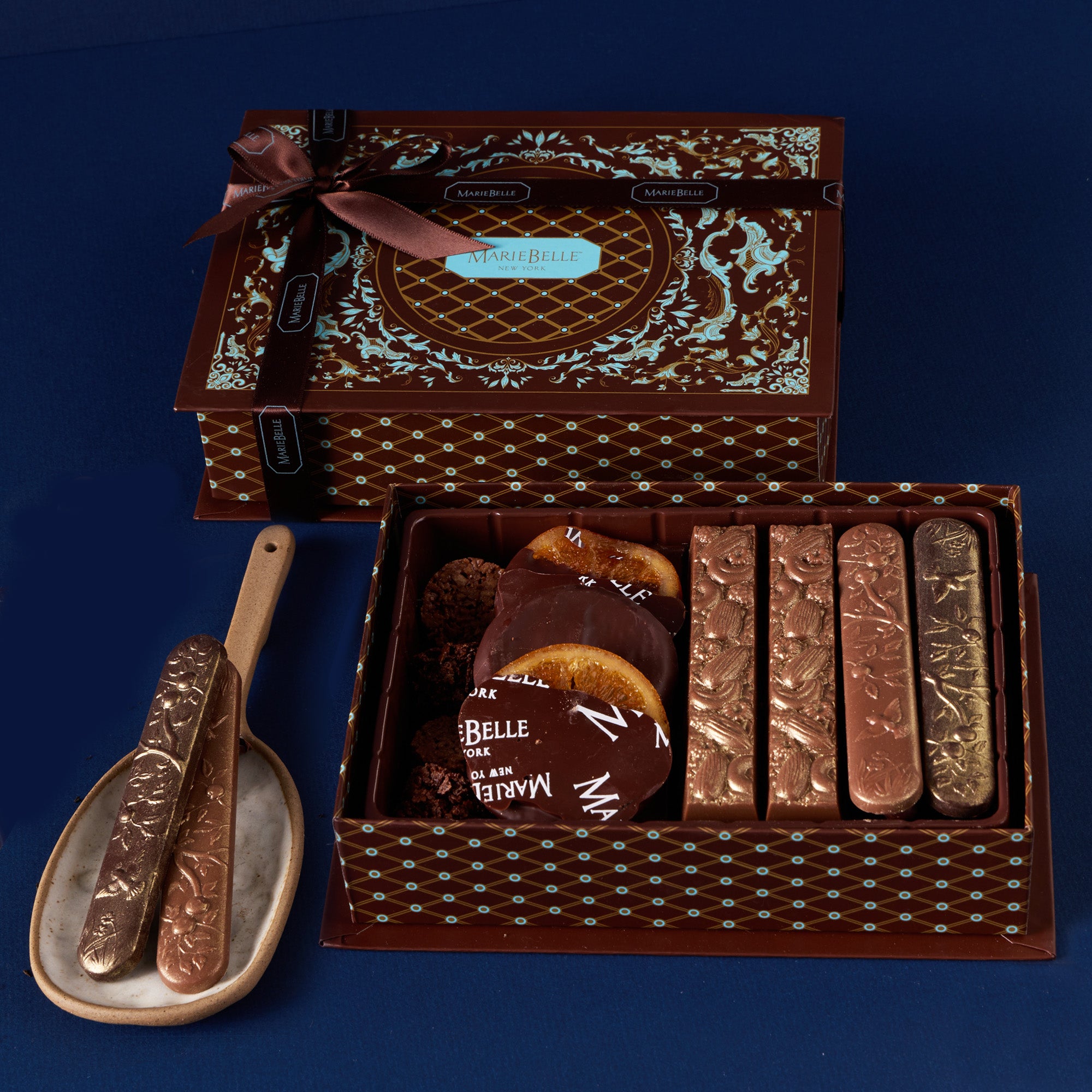 Decorative chocolate box with confections and serving utensils on a blue background