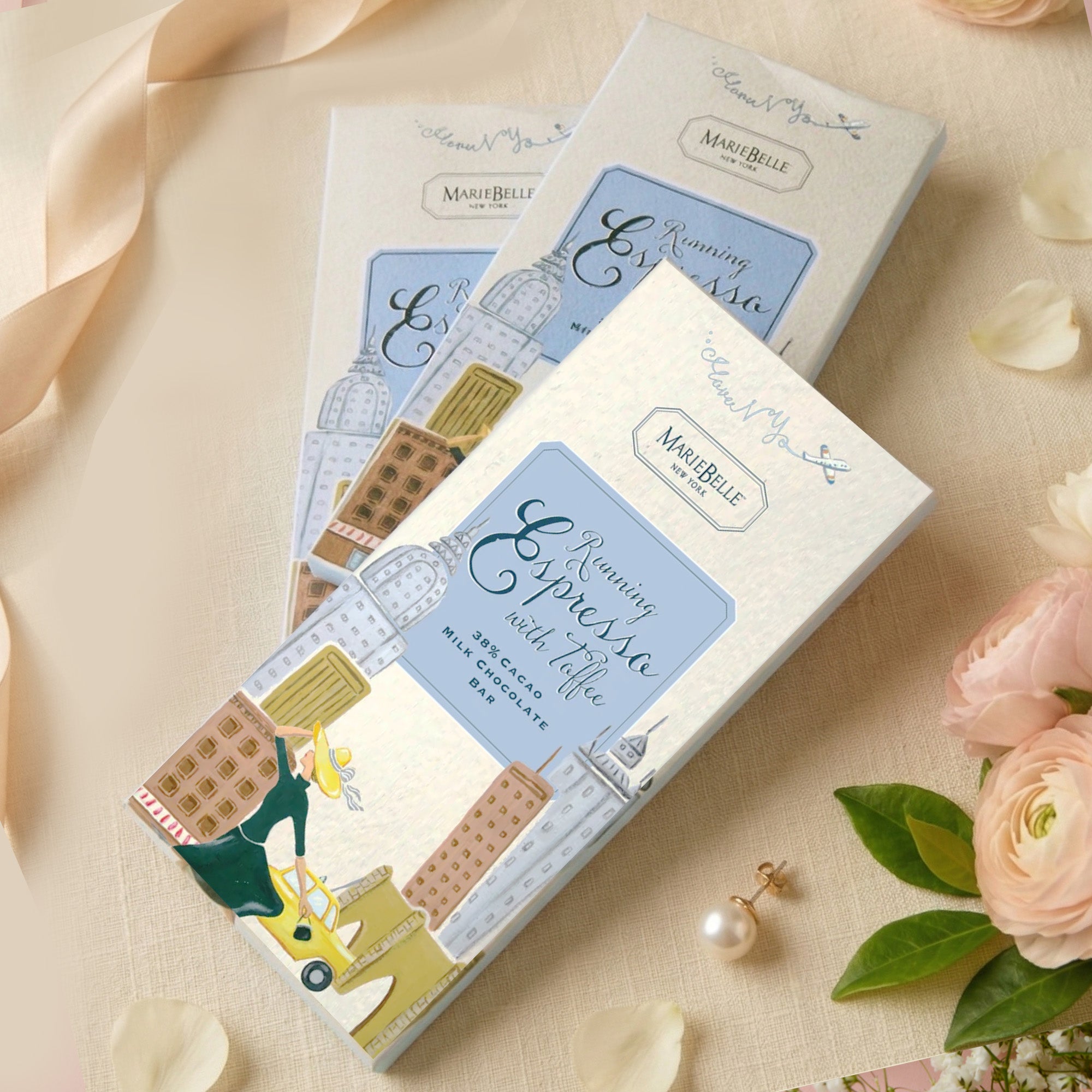 MarieBelle Chocolate bars with decorative packaging on a soft background with flowers and jewelry.