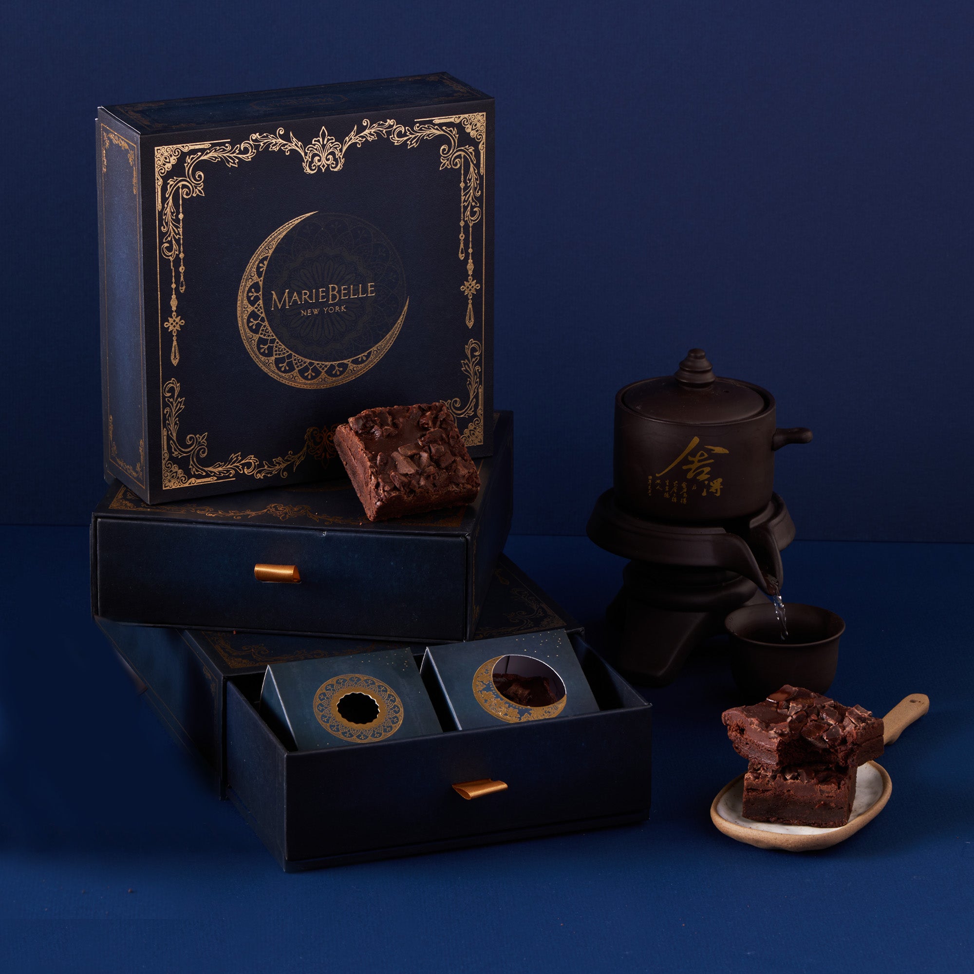 MarieBelle chocolate packaging with brownies and tea set on a blue background