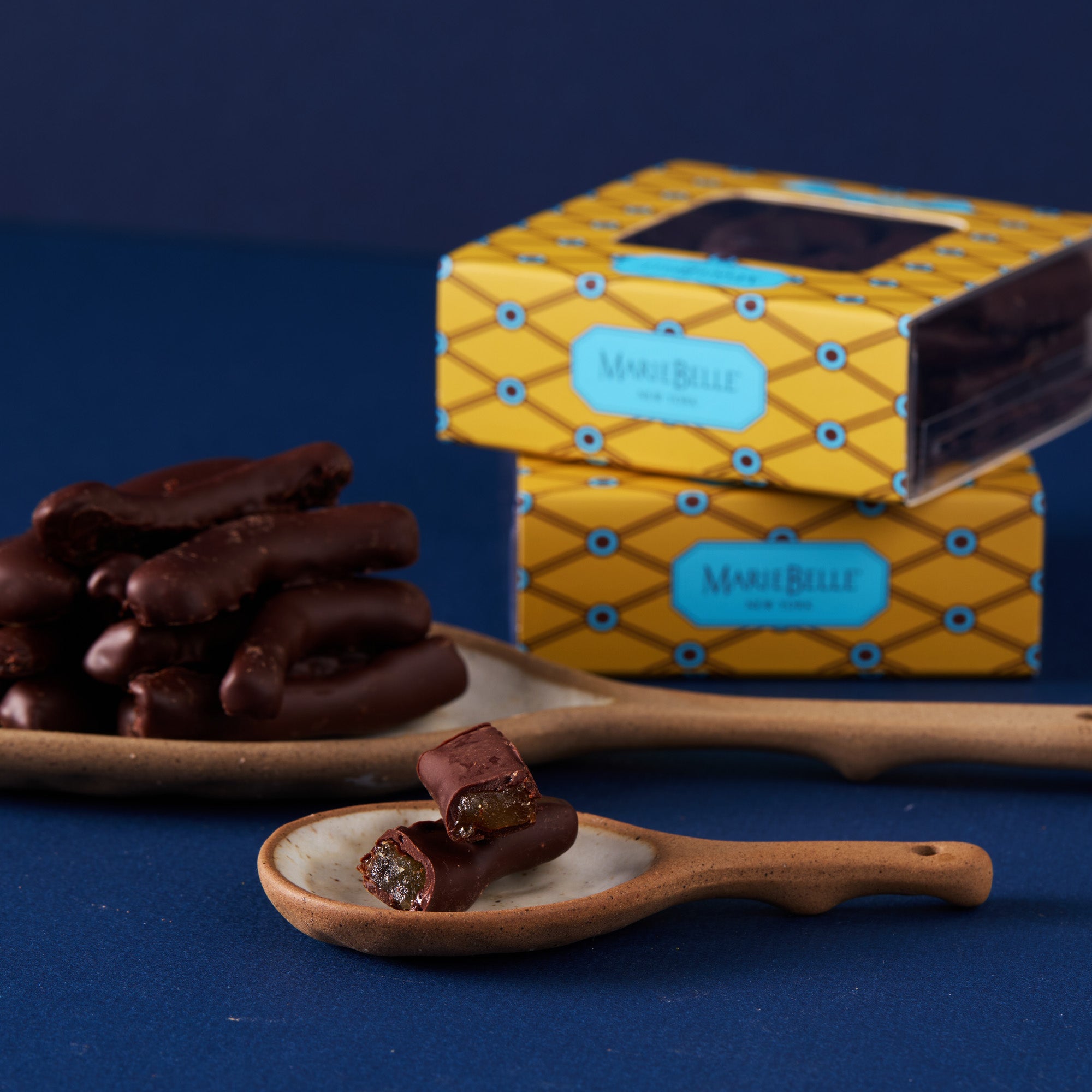 Chocolate lemon peels on a wooden spoon with a yellow gift box in the background