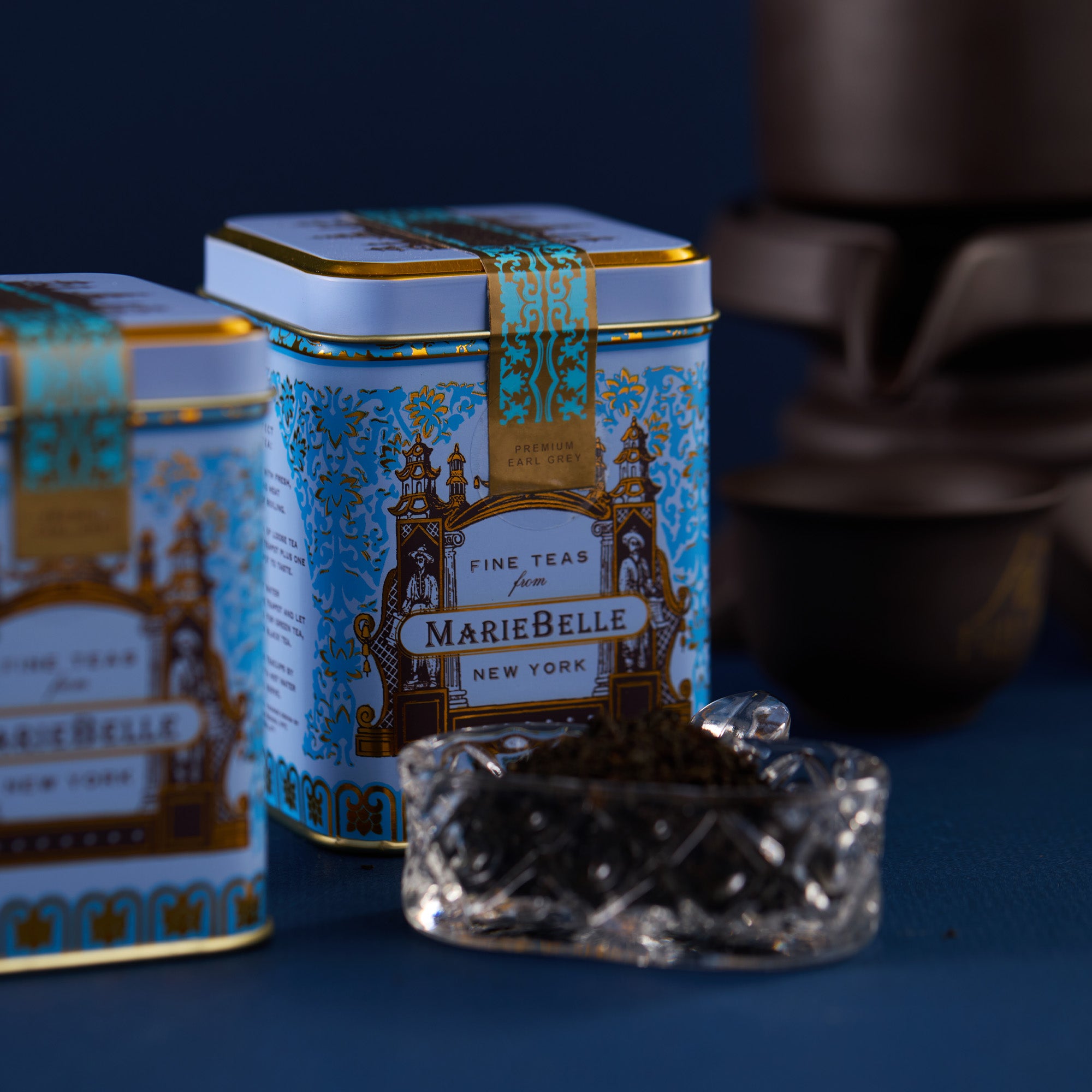 MarieBelle New York tea canisters with a decorative lid on a dark background