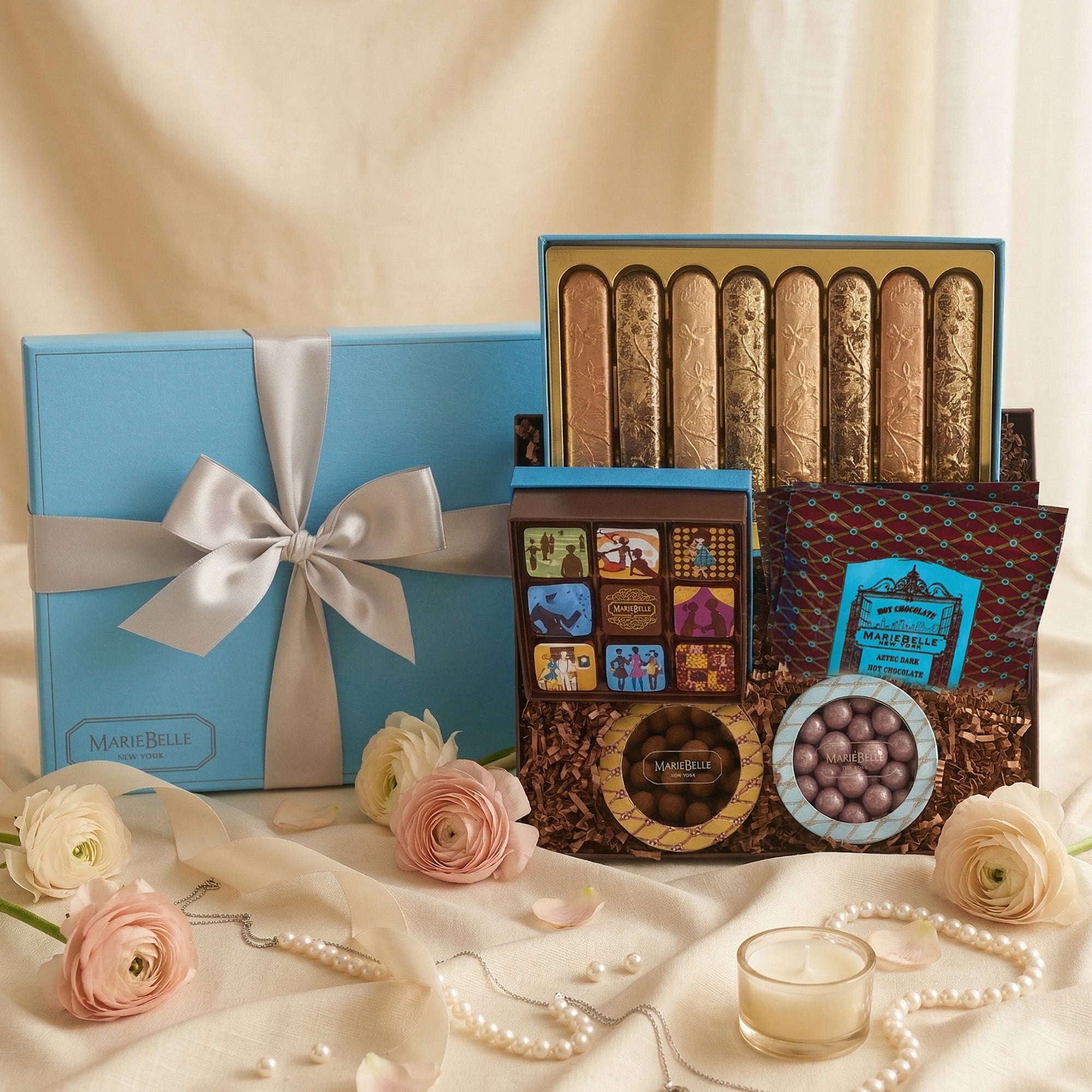 Gourmet Icaza chocolate set with a blue gift box, flowers, and jewelry on a beige background