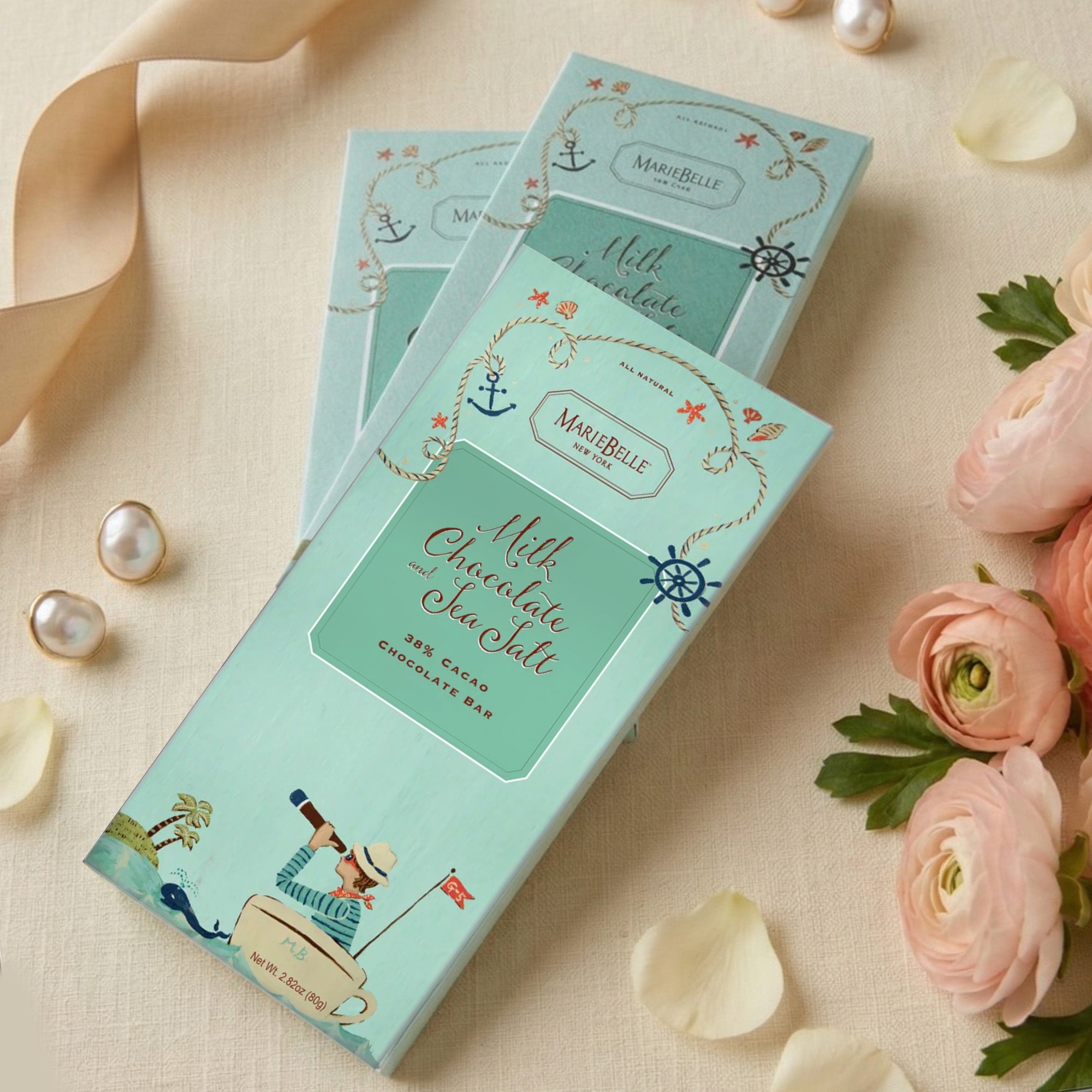 MarieBelle Chocolate bars with decorative packaging on a soft background with flowers and jewelry.