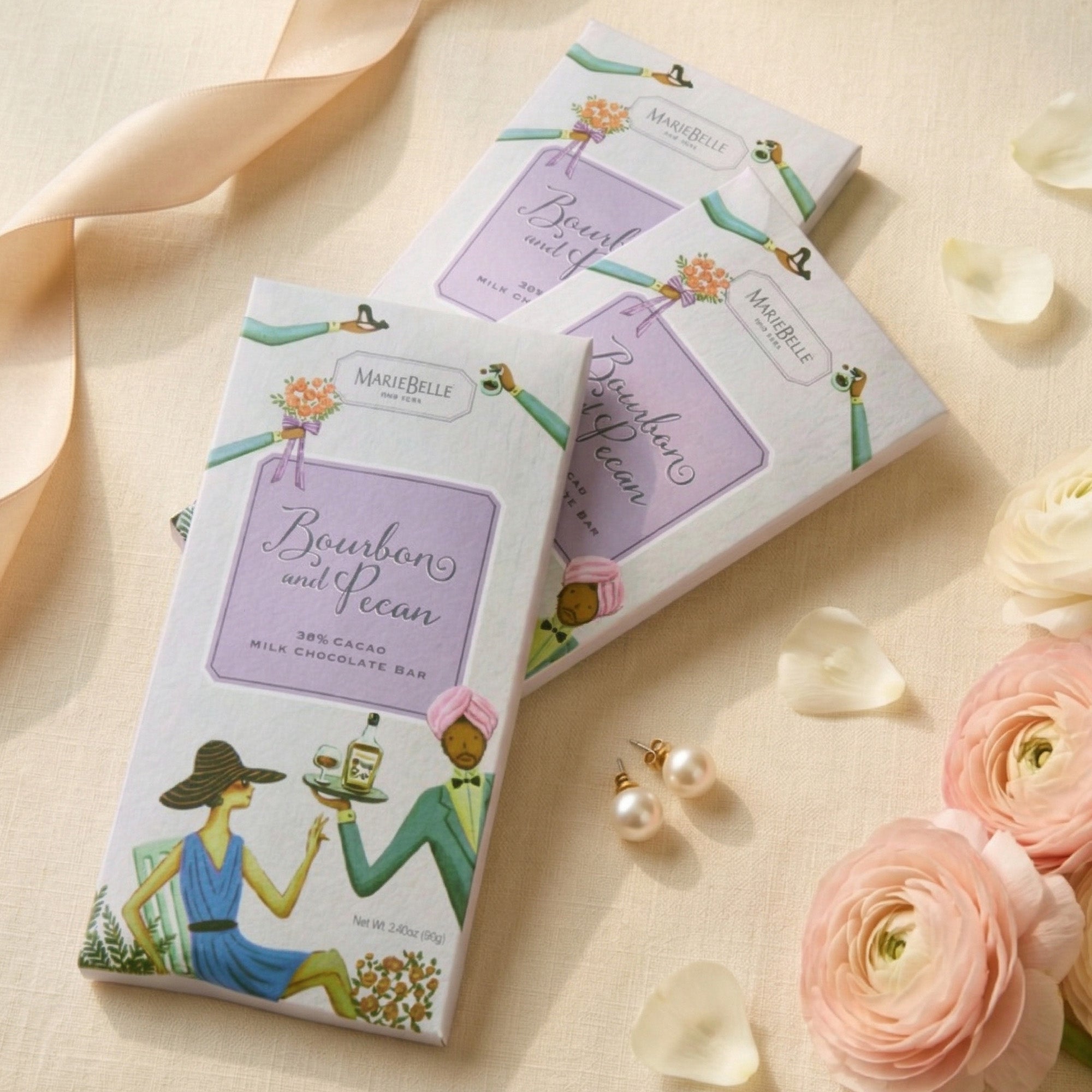 MarieBelle Chocolate bars with decorative packaging on a soft background with flowers and jewelry.